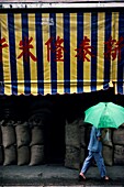 Frau mit Regenschirm, vorbei an Reismarkt, Hongkong