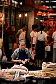Frau, die Lebensmittel auf einem Straßenmarkt in Hongkong verkauft