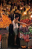 China, Hong Kong, Man wearing tank top and shorts picking out grapefruit in market