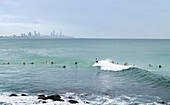 Surfers in the water on the coast of Burleigh Heads and Surfers Paradise in the horizon