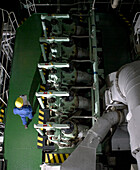 Aerial view of engineer with maintenance chart in ships engine room conducting a check