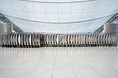 Neatly stacked row of stainless steel airport baggage carts placed against a background of contemporary designed Airport Lobby