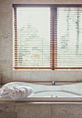 Luxury spa bath surrounded by marble underneath window in bathroom