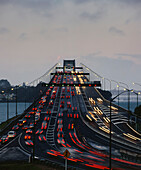 Der Verkehr fließt in der Abenddämmerung auf der Auckland Harbour Bridge in beide Richtungen