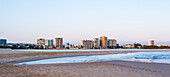 Looking across beach at low tide and early morning to Maroochydore township and high rise buildings