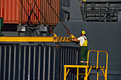 Man securing shipping container for loading on ship