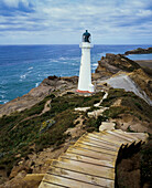 Eine Reihe von Holzstufen, die zum Castle Point Lighthouse auf einer felsigen Klippe und einem blauen Pazifischen Ozean führen