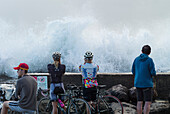 Menschen auf dem Bürgersteig beobachten riesige Wellen, die vom Zyklon Ola abstürzen