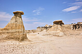 Low angle wide landscape of sandstone hoodoos at Ah-shi-sle-pah Wilderness Study Area in New Mexico. Area is located in northwestern New Mexico and is a badland area of rolling water-carved clay hills. It is a landscape of sandstone cap rocks and scenic olive-colored hills. Water in this area is scarce and there are no trails; however, the area is scenic and contains soft colors rarely seen elsewhere