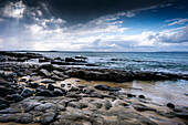 Stormy sky over rocky shoreline at low tide