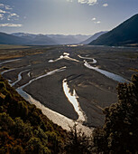 Shingle river bed low in water surrounded by Southern Alps in Arthurs Pass, South Island, New Zealand