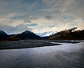 Snow capped mountains line Rees River as it runs into the head of Lake Wakatipu in Glenorchy