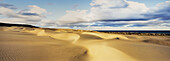 Panorama of large sand dunes rolling down to the coast meeting the Coral Sea and dramatic clouds in the sky on Fraser Island - Queensland