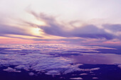 Looking down at top of clouds and sun setting