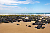 Sanfte Welle, die auf glatte Felsen am Strand von Fraser Island schwappt