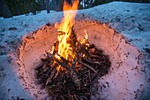 Campfire buring in snow in twilight in Sky Lakes Wilderness