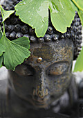 buddhistische Gartenfigur und Ginkgoblätter