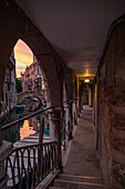 Durchgang und kleiner Kanal mit Brücke in Venedig im Abendlicht, Italien