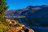 Stadtbild und Luganersee mit blauem Himmel und Berg an einem sonnigen Tag in Morcote, Tessin in der Schweiz