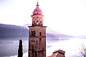 Kirchturm Santa Maria del Sasso mit Sonnenlicht und Berg am Luganersee in Morcote, Tessin in der Schweiz