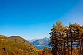 Panoramablick über das Dorf Menaggio mit dem Comer See mit Bergen an einem sonnigen Tag im Herbst in der Lombardei, Italien