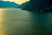 Segelboot auf dem Luganersee mit Sonnenlicht und Berg in Lugano, Tessin in der Schweiz.