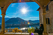 Frau genießt Bergblick an einem sonnigen Wintertag vor der Kirche dei Santi Quirico e Giulitta in Lugano, Tessin in der Schweiz