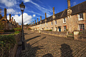 View down the ancient Vicar&#39;s close lane in Wells, Somerset, England in sunshine and puffy clouds.