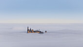 A distant view of Hohenzollern Castle above the clouds. Pfeffingen, Albstadt, Baden-Würtenberg, Germany.