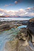Rock formations at Steinsvika beach. tide pool. mountain in the background. Storslett, Troms, Norway.