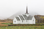 Kirche im Nebel vor Berg. Langenes, Sto, Nordland, Norwegen.