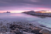 Felsküste am Strand von Fjaervollsanden. Trockenfisch Gestelle, Sonnenuntergang, Gimstad, Nordland, Norwegen.
