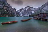 Hut on stilts with rowing boats in the mountain lake Pragser Wildsee, Braies, South Tyrol, Italy.