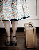 Woman with skirt next to leather suitcase