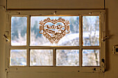 Wooden decorative heart with Almabtrieb motif in old door window, farmhouse in Upper Bavaria