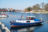 Blaues Fischerboot am alten Strom in Warnemünde in Richtung Bahnhofsbrücke am Morgen, Rostock, Mecklenburg-Vorpommern, Deutschland