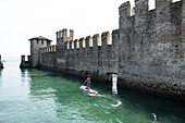 SUP paddlers in front of Sirmione Castle, Verona District, Veneto, Italy