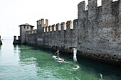 SUP Paddler vor dem Schloss von Sirmione, Verona District, Venetien, Italien