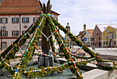 mit bunten Ostereiern geschmückter Brunnen auf dem Schrannenplatz in Erding, Bayern, Deutschland