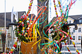 mit bunten Ostereiern und farbigen Bändern geschmückter Osterbrunnen in Muggendorf in der Fränkischen Schweiz, Bayern, Deutschland