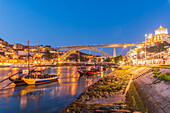 Barcos Rabelos, port wine boats on the Duero River in front of the Dom Luís I Bridge and the historic old town of Porto at night, Portugal