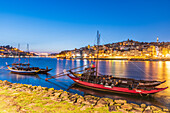 Barcos Rabelos, Portweinboote auf dem Fluss Duero vor der historischen Altstadt von Porto bei Nacht, Portugal