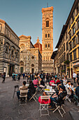 Evening people at cafe/restaurant in front of baptistery and facade of Duomo, Cathedral of Santa Maria del Fiore, Florence, Tuscany, Italy