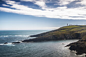 Gallyhead Lighthouse stands in the distance on headland. Sunshine. Dundeady, Rathberry, County Cork, Ireland.