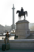 Girl on phone with suitcases, Trafalgar Square, London, UK