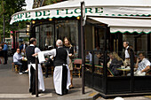 Waiters talking to a young woman and people sitting outside Cafe de Flore, Blvd St Germain, Paris, France