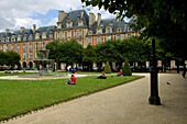 Brunnen im Park und Menschen, die sich auf dem Rasen entspannen, Place des Vosges, Marais, Paris, Frankreich