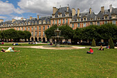 Place des Vosges with fountain and people relaxing in summer sun, The Marais, Paris, France