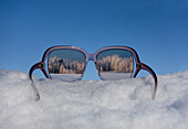 Blick auf die verschneite Winterlandschaft durch eine Sonnenbrille, Reflexion