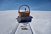 Schlitten, der Picknickkorb über hügelige, verschneite Winterlandschaft transportiert